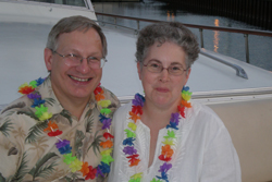 A man and a woman stand on a boat wearing colorful lei necklaces